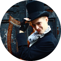 Russell Patrick Brown holding a harp in right hand and tipping top hat with left hand in Steampunk outfit