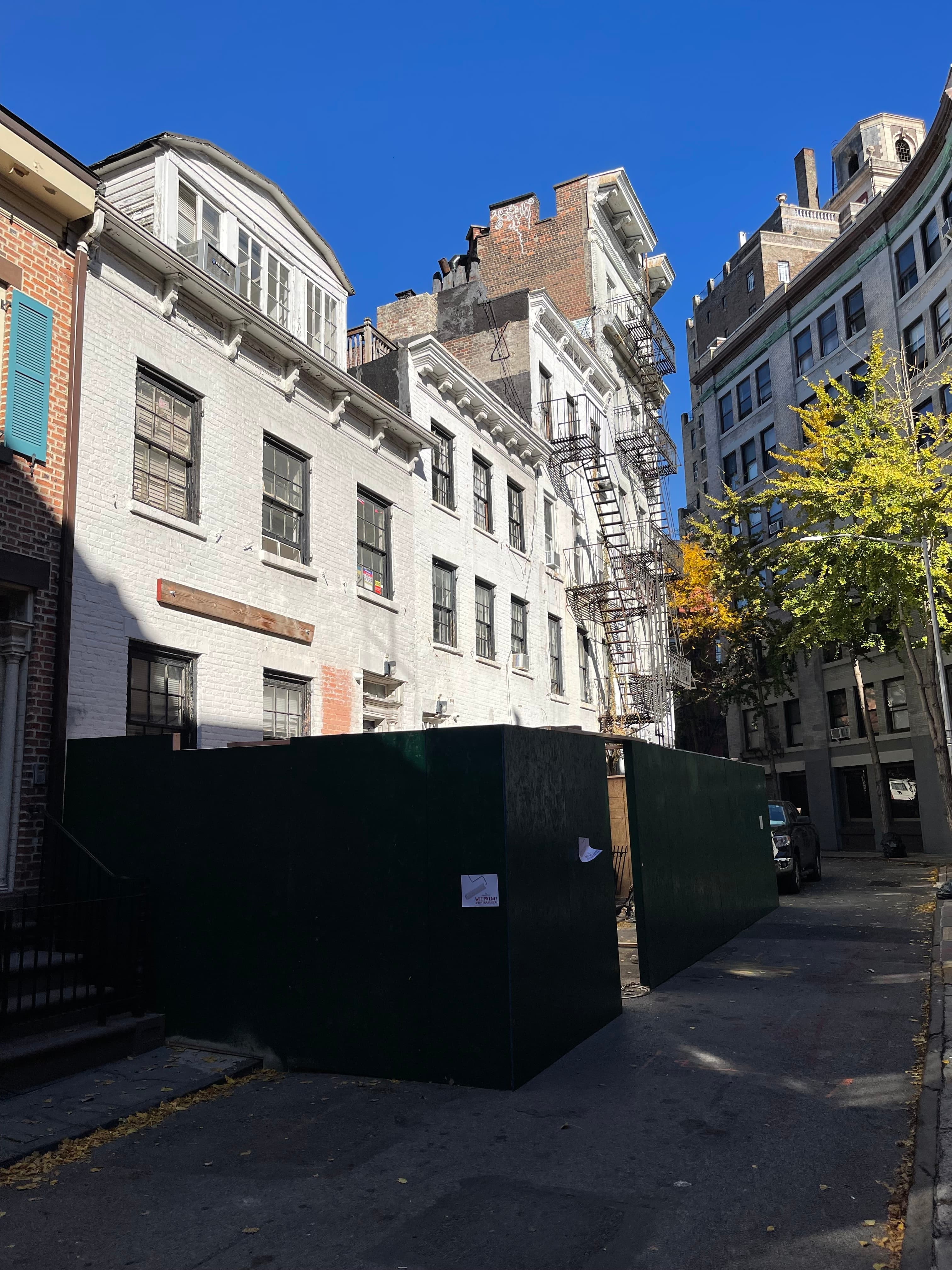 Green sidewalk sheds and construction fencing enclosing the fronts of 14–18 Gay Street, a section of 14 Gay's facade peeling away, November 8, 2022