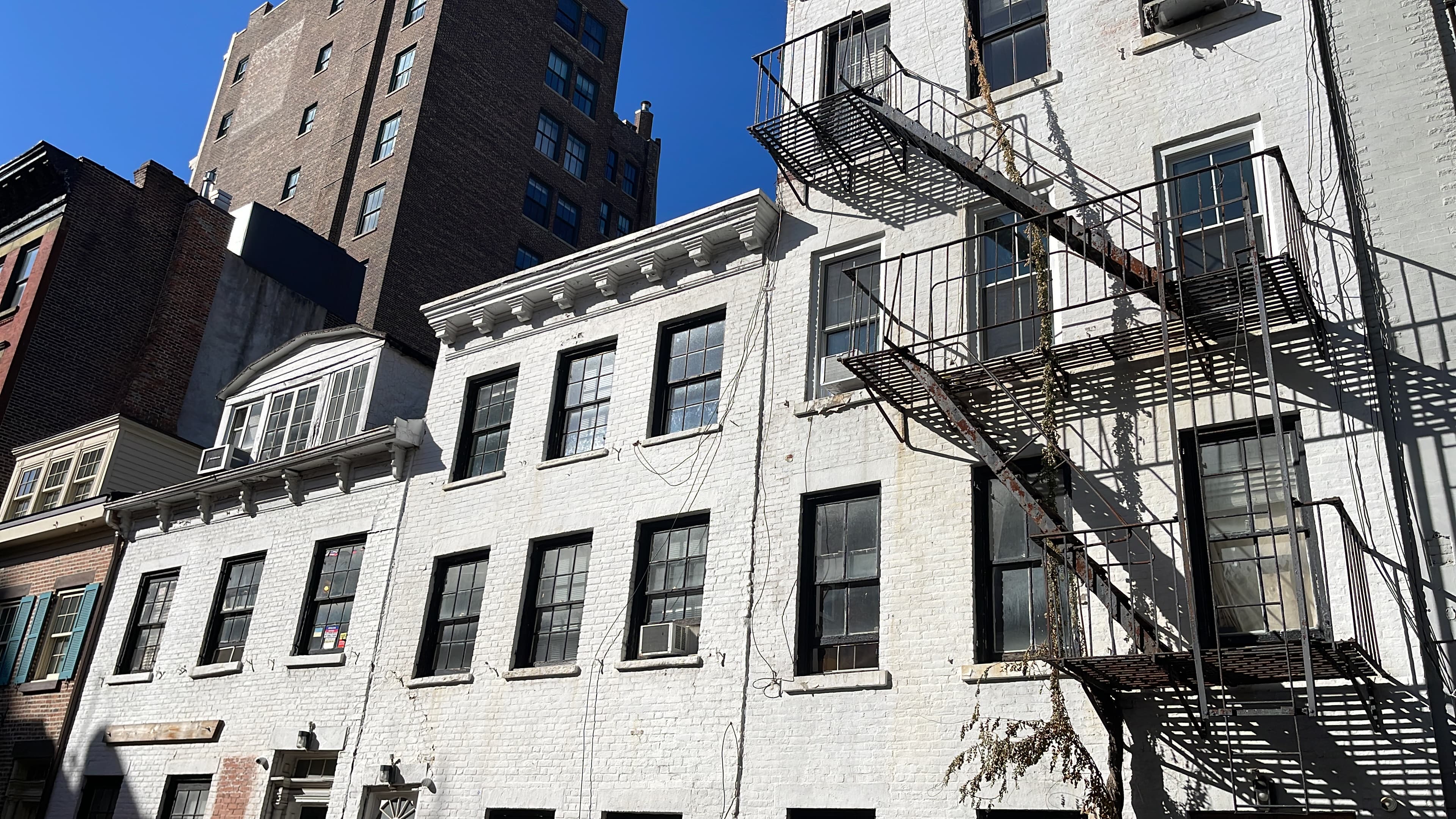 Cracks running down the facades of the adjoining white houses at 14–18 Gay Street, a posted notice in a second-floor window, November 10, 2022