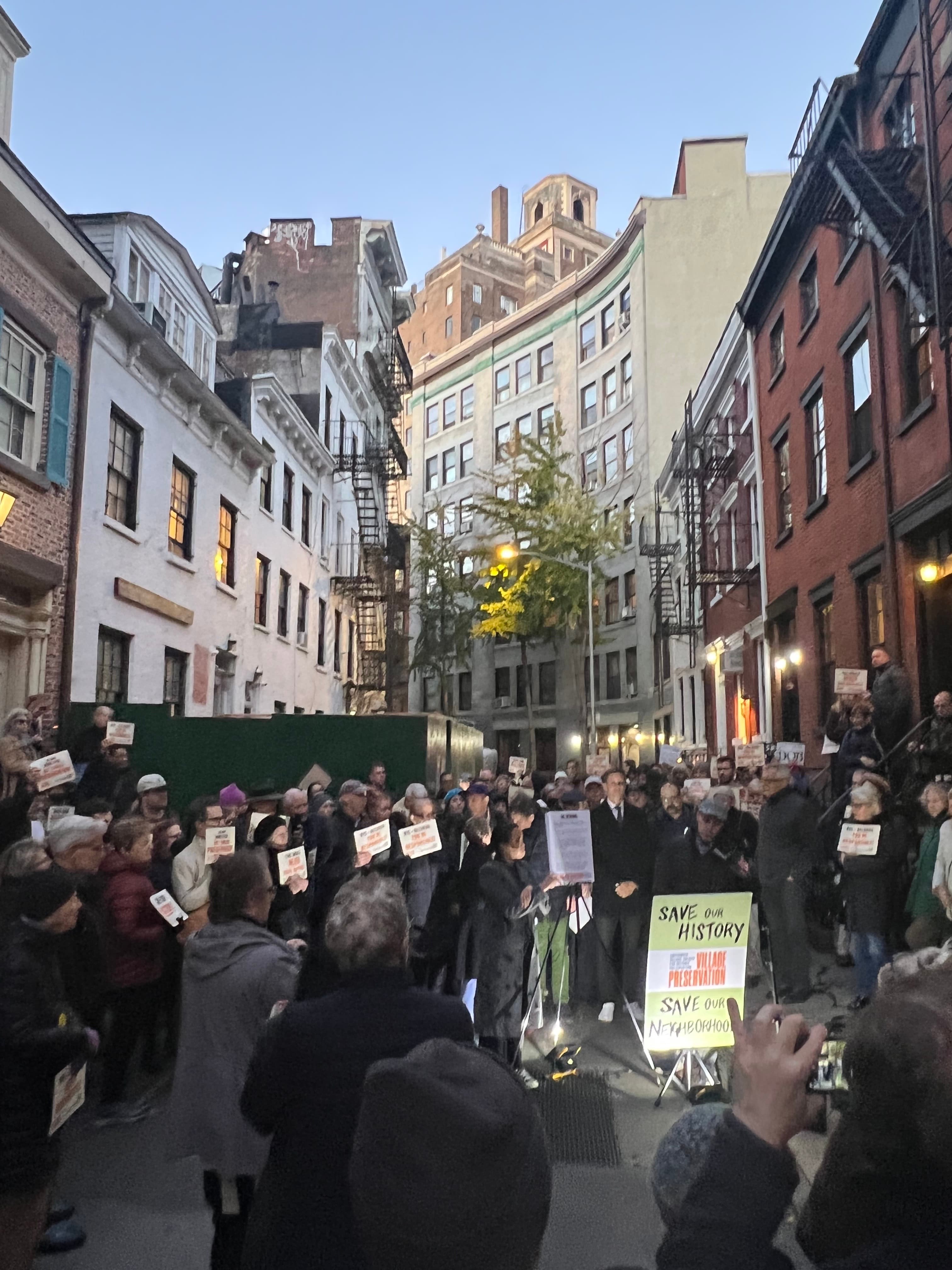 Protesters fill the bend of Gay Street on November 14, 2022, holding Village Preservation signs in front of the construction fencing around 14 Gay Street