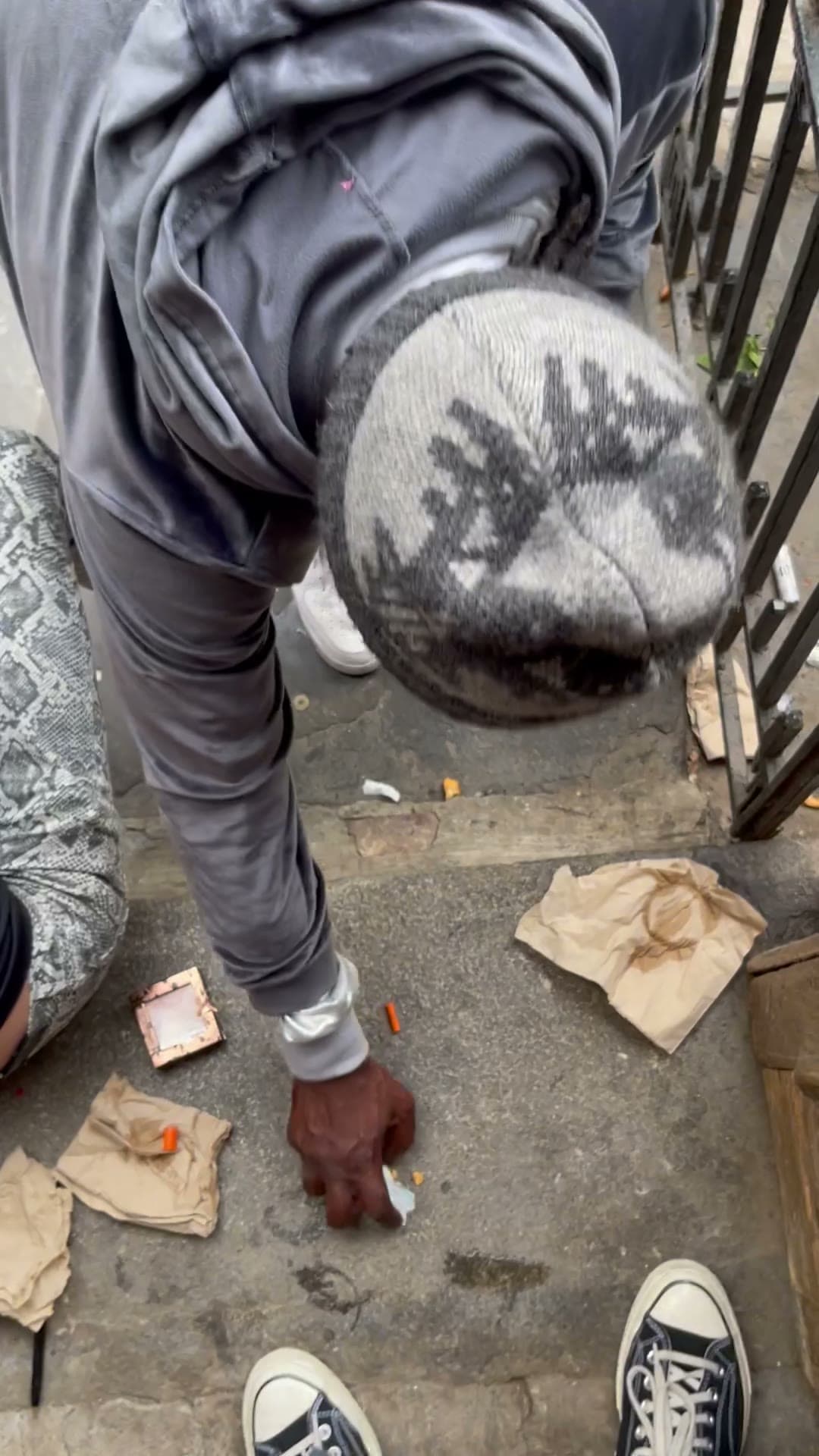 Video frame of a person crouched at the door of 18 Gay Street with drug paraphernalia on the pavement, June 18, 2023