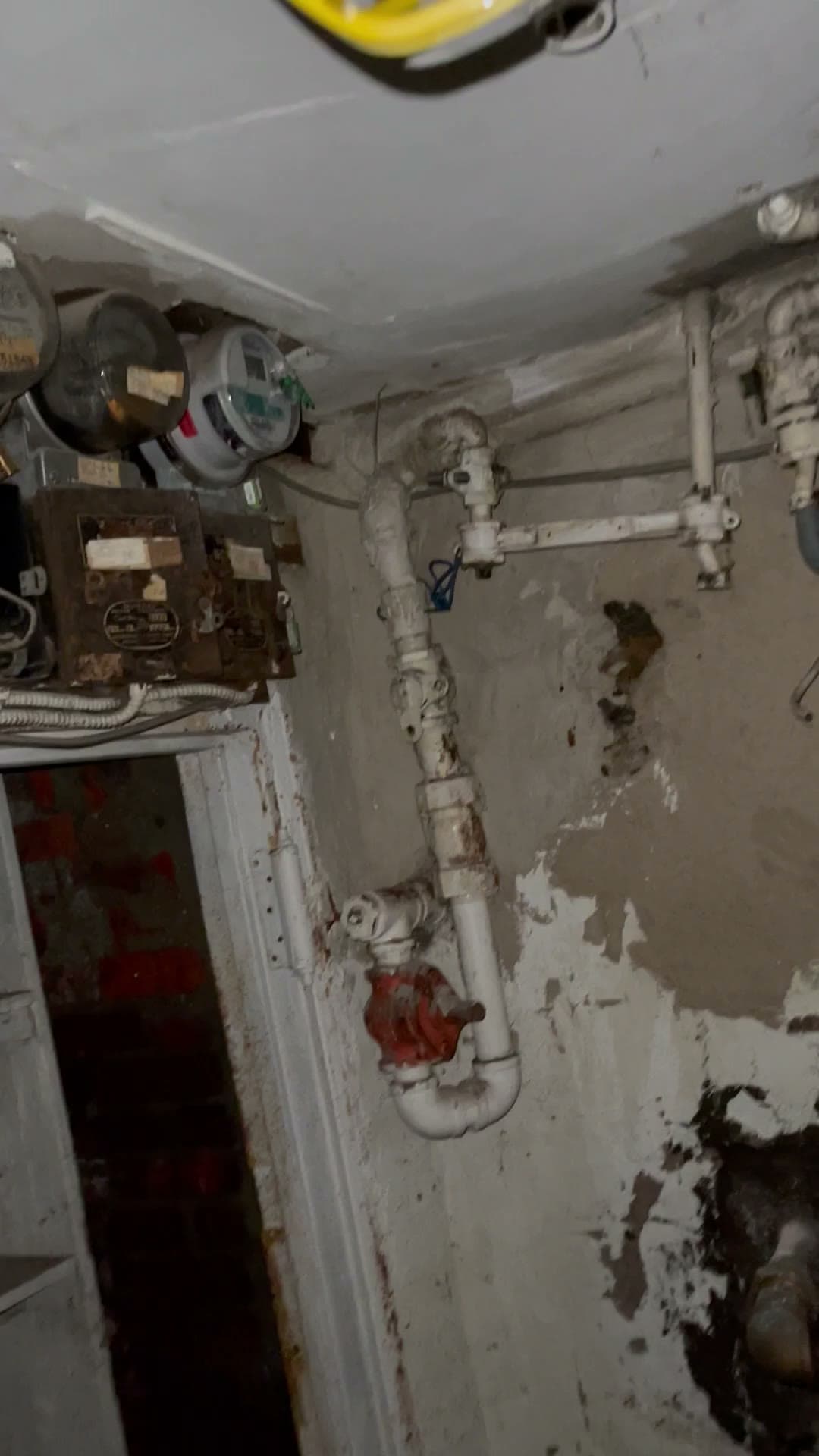 Video frame from the basement of 18 Gay Street showing old electric meters, a rusted fuse cabinet, and deteriorated wiring and pipes
