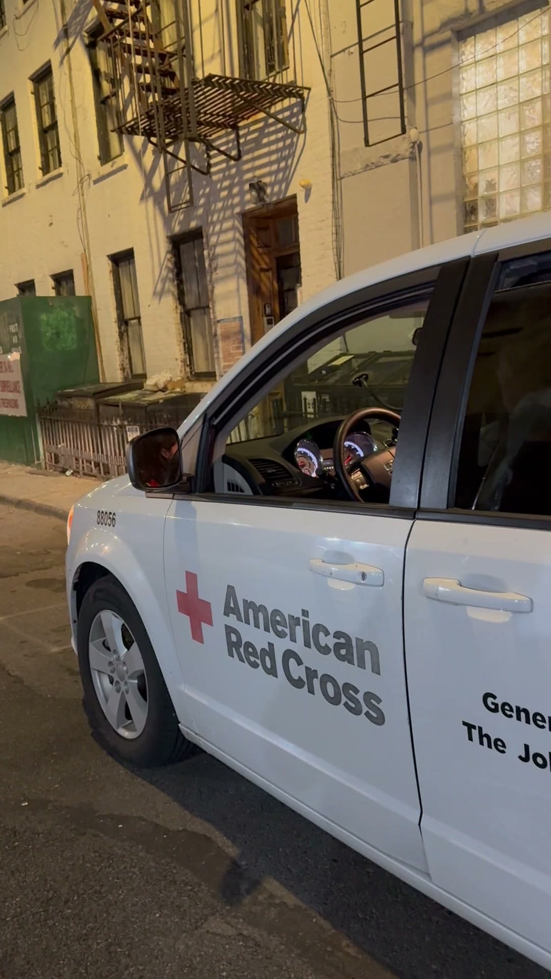 An American Red Cross van parked on the street outside 18 Gay Street at night, the vacated building's facade and fire escape behind it, April 27, 2025