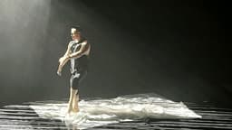 Russell bailando sobre una lona blanca bajo una iluminación en rejilla