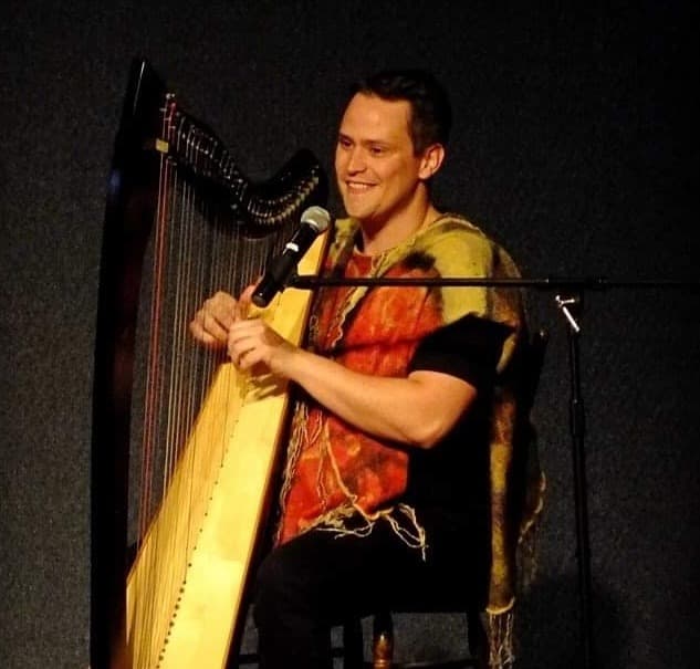 Russell Patrick Brown playing harp and singing on stage